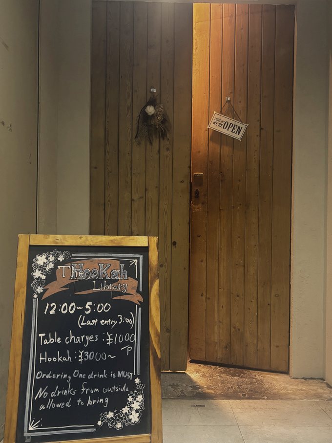 夜に暖色の灯りがこぼれる木の扉と黒板の看板、OPENの札